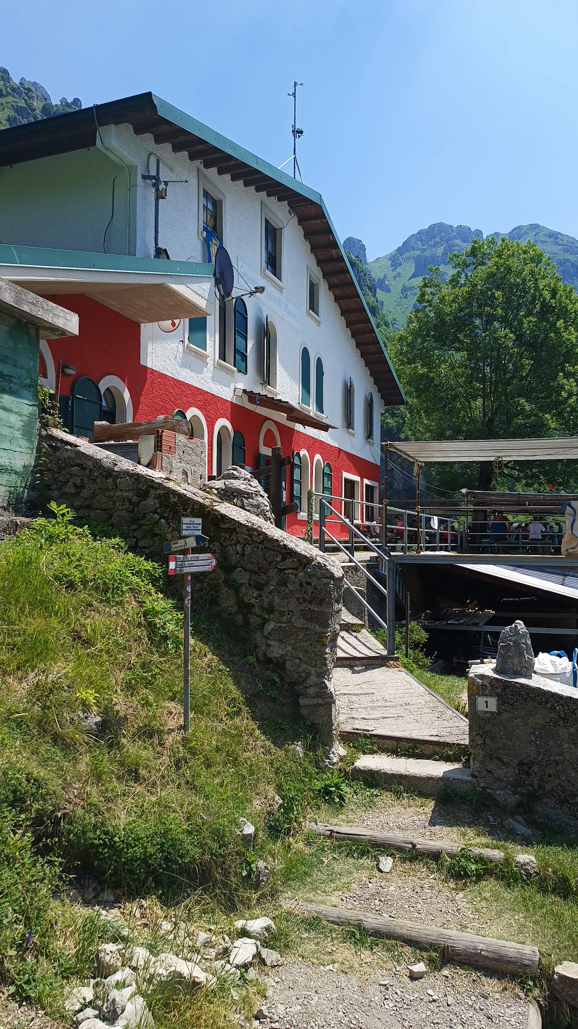 Facciata del Rifugio Capanna Alpinisti Monzesi con pareti rosse e bianche immerso nel verde del Resegone